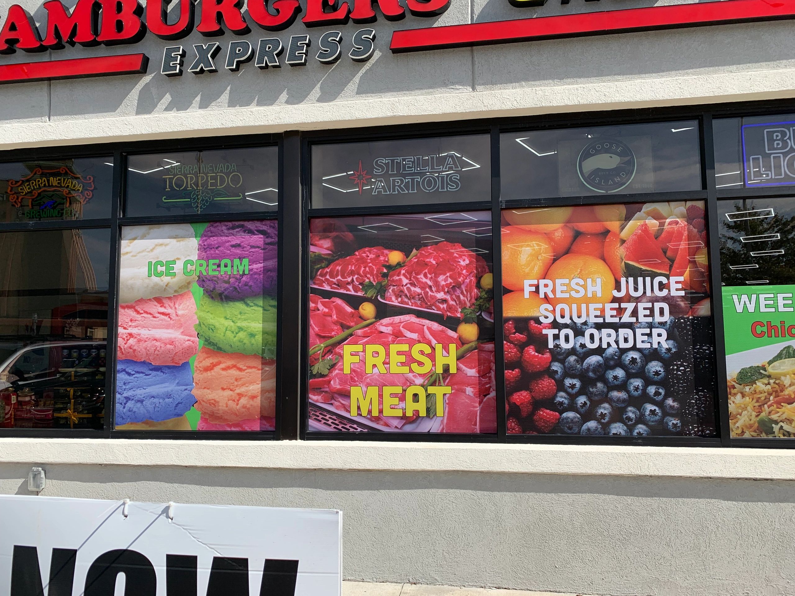 Storefront window graphics showcasing Hamburgers Express, Ice Cream, Fresh Meat, Fresh Juice, Stella Artois, Sierra Nevada Torpedo, and Goose Island